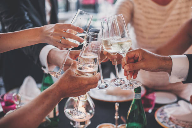 celebración navideña de lujo. la gente brinda con copas de champán en un delicioso banquete al aire libre por la noche. gafas de zumbido familiares y amigos y animando con alcohol - restaurant banquet table wedding reception fotografías e imágenes de stock