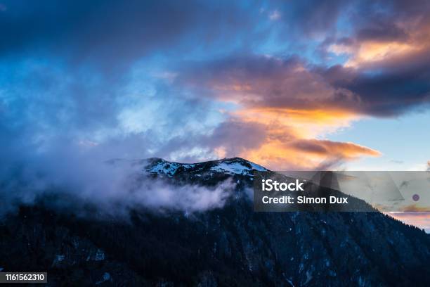 Montenegro Snow Covered Peak Of Durmitor Mountains Hidden By Fog And Glowing Red Clouds In Magical Dawning Atmosphere At Sunset On Summit Of Mount Curevac In National Park Near Zabljak Stock Photo - Download Image Now