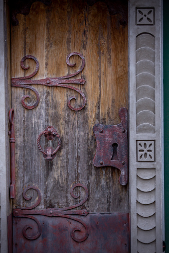 wooden, ancient door entrance with decorative ironwork and iron doorknob and door lock