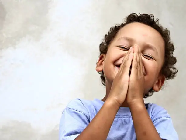 little boy praying to God stock image with hands held together with closed eyes stock photo