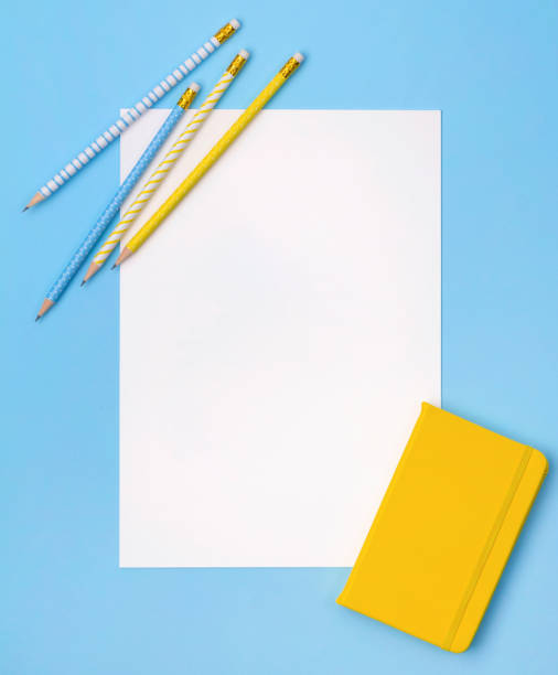 istock White sheet of paper with notepad and pencils on pastel blue background. 1161566450