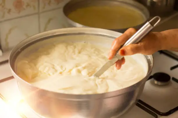 Hands of senior woman who is making homemade yogurt ( yogurt ) with selective focus. Fermentation of yoghurt with blurred background.