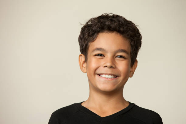 Closeup studio portrait of a 12 year old boy on a beige background stock photo