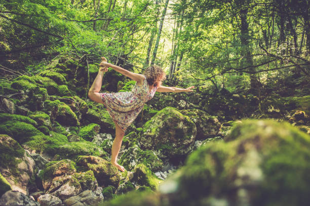 Woman meditation and doing yoga in a green forest.