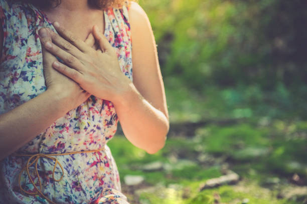 fermez-vous vers le haut de la méditation dans une forêt verte - spirituality hand on heart meditating women photos et images de collection