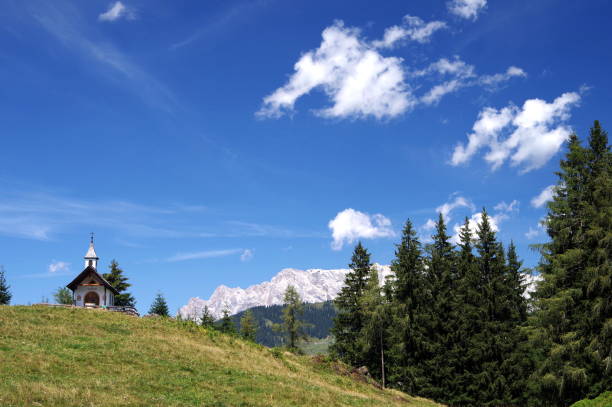 istock Mountain chapel with plank fence under blue sky with mountains in the background 1161574829