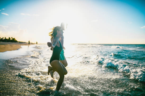 Group of playful friends having fun while splashing during summer sunset in the sea. Copy space.