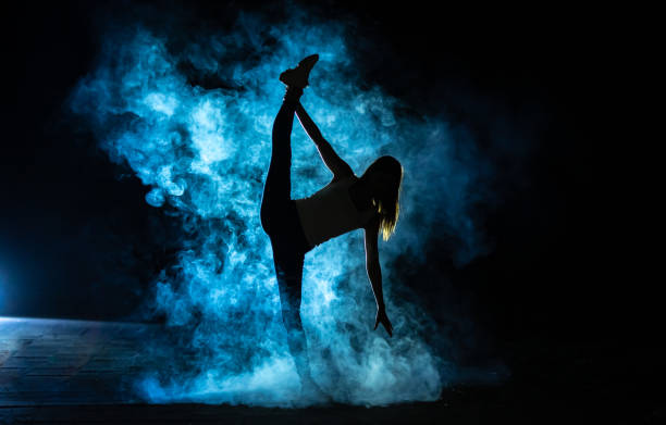 istock The gymnast doing vertical split in the smoke on the dark background 1161582668