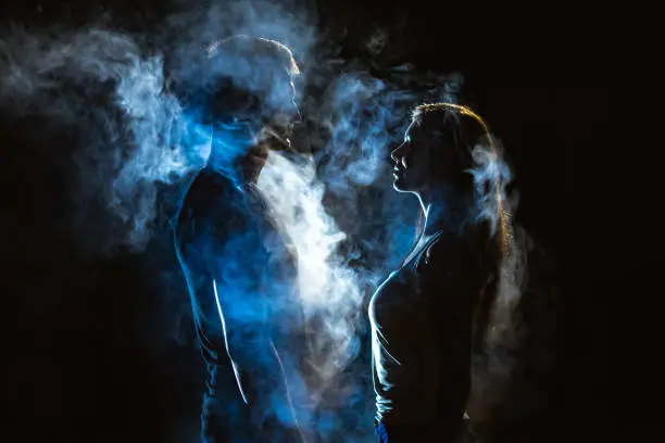 Photo of The man and woman standing in smoke on the dark background