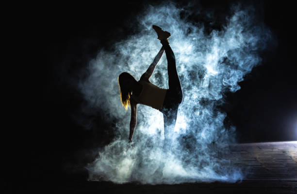 istock The gymnast doing vertical split in the smoke on the dark background 1161584611