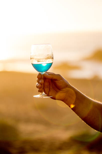 Mens hand holding glass of spanish blue with wine on sea ocean background Mens hand holding glass of spanish blue with wine on sea ocean background. chilean wine stock pictures, royalty-free photos & images