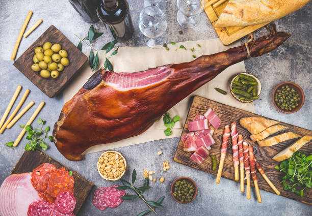 istock Appetizers table with spanish iberian whole ham jamon serrano, snacks, olives and red and rose wine. Flate lay. Top view. Gray background 1161586689