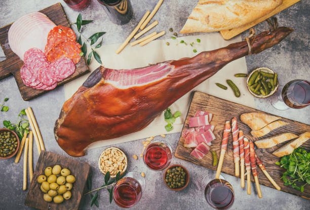 istock Appetizers table with spanish iberian whole ham jamon serrano, snacks, olives and red and rose wine. Flate lay. Top view. Gray background 1161586690
