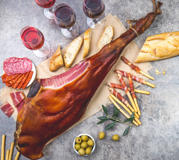 istock Whole leg HAM JAMON SERRANO and red and rose wine on gray background. Top view. Flat lay 1161586798