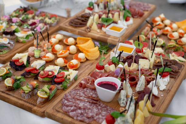 Large selection of food with cold snacks, salads, cold meats, cheese and jam served. Variety of tasty delicious snacks on the table. Wedding reception stock photo