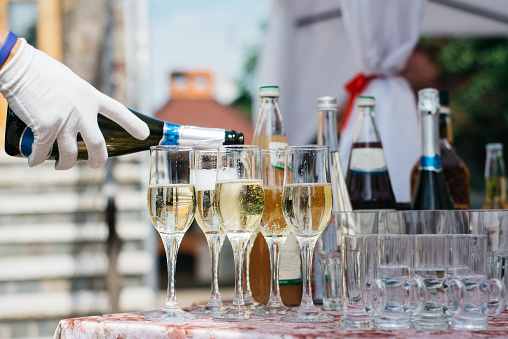 Bartender pours champagne. A lot of wine glasses with cool delicious champagne or white wine. Party and holiday celebration concept