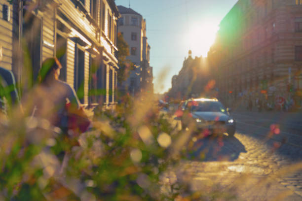 A couple walking down the street in the city of Riga on a sunny day next to cars in backlight