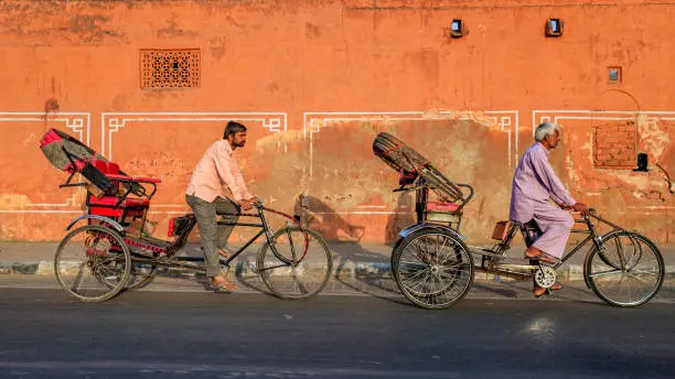 Indian men ride cycle rickshaw on streets of Rajasthan, India.