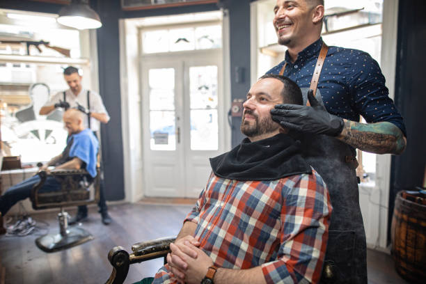 istock Cheerful barber massaging customer's beard before shaving 1161592578