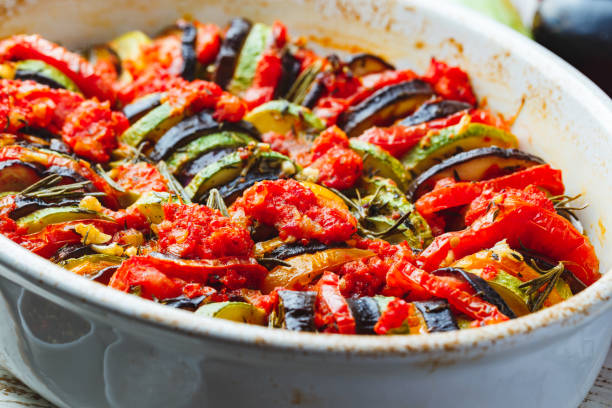 Vegetable ratatouille in ceramic frying pan Vegetarian ratatouille from eggplants, zucchini, tomatoes and bell pepper sauce and tomato with herbs in ceramic form before baking. Rustic style. Close up. ratatouille stock pictures, royalty-free photos & images