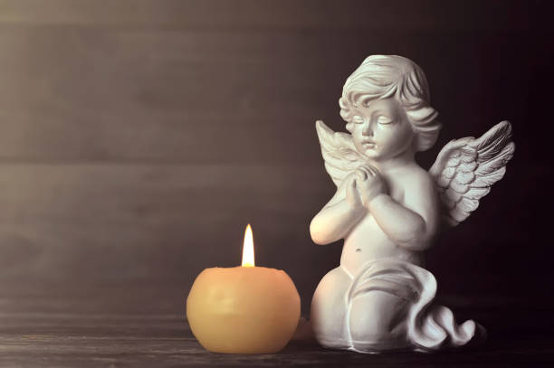 istock Angel and candle on dark background 1161596197
