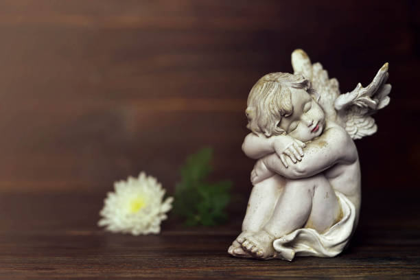istock Cherub and white flower on dark background 1161596208