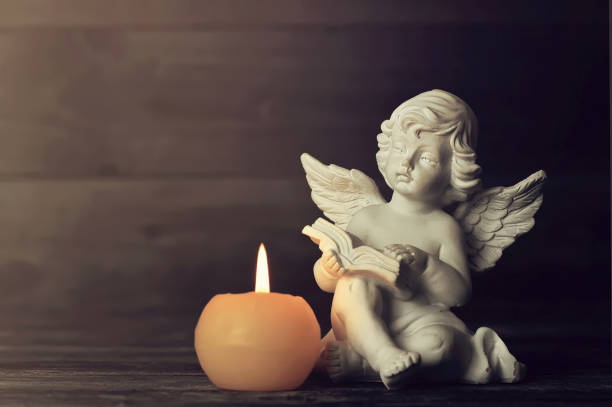 istock Angel and white candle on dark background 1161596249