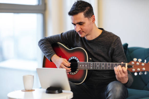 istock Young Man Learning To Play Acoustic Guitar From Digital Tablet 1161597197