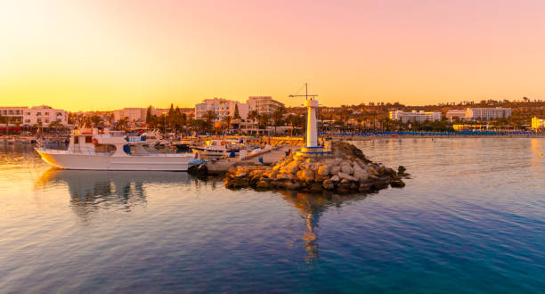 Agia Napa marina view on sunset with fishing boats stock photo Ayia Napa, Cyprus - May 01, 2018: Ayia Napa harbor and lighthouse. Tourist boats and fishing boats. Sunset time. People on the background. cyprus agia napa stock pictures, royalty-free photos & images
