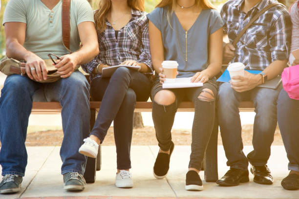 istock College student friends sitting on university campus bench. 1161598321