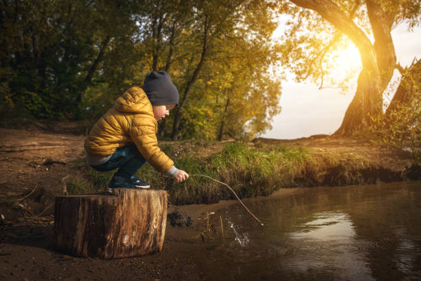 Little boy plays with stick at the lake.