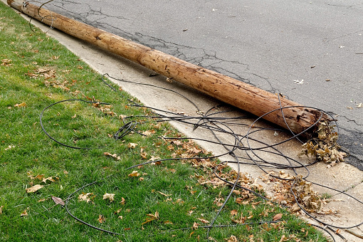 Downed utility pole lying on residential neighborhood street.