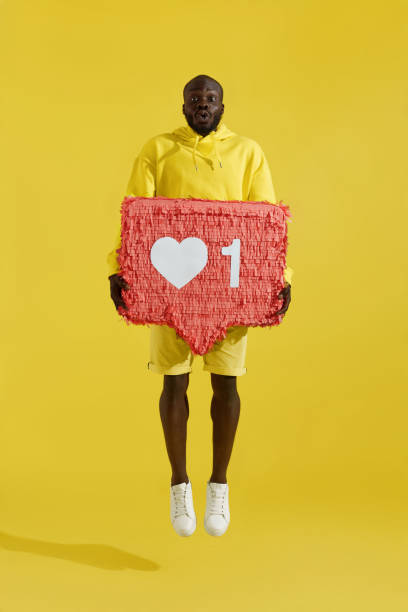 istock Like. Surprised man jumping with heart icon pinata on yellow 1161604222