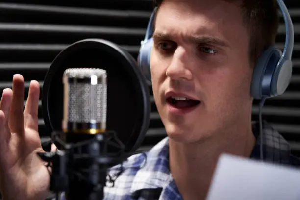 Man In Recording Studio Reading From Script Into Microphone