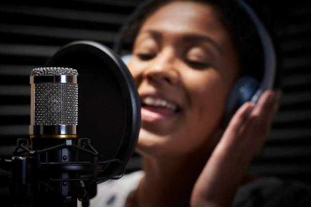 vocalista femenina usando auriculares cantando en el micrófono en el estudio de grabación - diva papel social fotografías e imágenes de stock