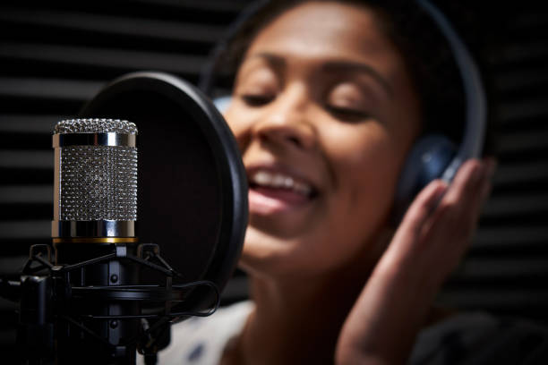 chanteur féminin utilisant des écouteurs chantant dans le microphone dans le studio d'enregistrement - african descent audio photos et images de collection