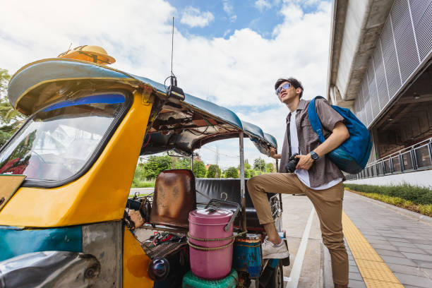 young asian traveller man standing with local tuk tuk taxi, khonkaen city, thailand - jinrikisha thailand tuk transportation imagens e fotografias de stock