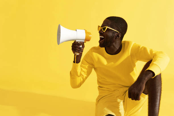 istock Man screaming in megaphone on yellow background portrait 1161608400