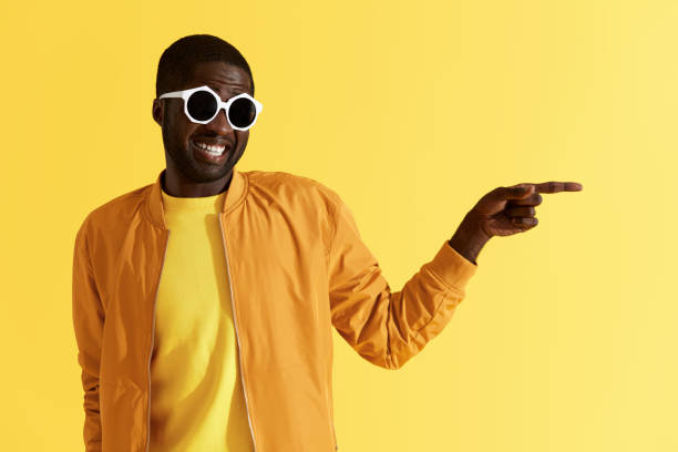istock Smiling man pointing on copy space on yellow background portrait 1161609460