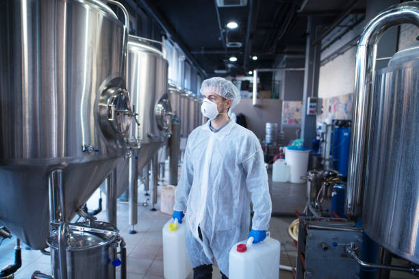 istock Technologist industrial worker holding plastic canisters about to change chemicals in the food processing machine. Cleaning in food factory. 1161609560