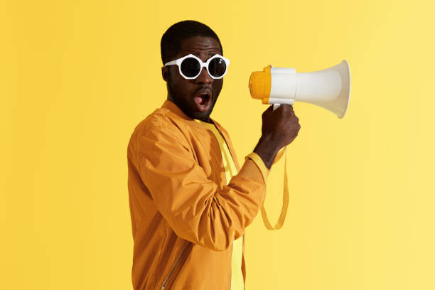 istock Surprised black man with megaphone on yellow background 1161609860