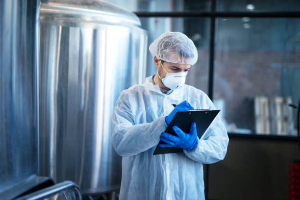 Concentrated technologist expert in white suit controlling production in food factory. Concentrated technologist expert in white suit controlling production in food factory. technology office equipment laboratory stock pictures, royalty-free photos & images