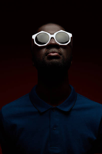Black man face in sunglasses in darkness, studio portrait