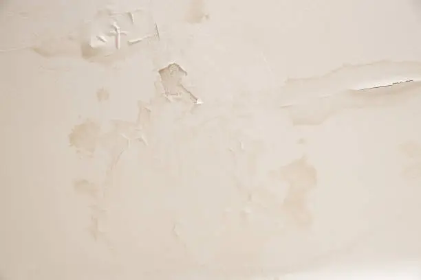 Photo of Big wet spots and cracks on the ceiling of the domestic house room roof after heavy weather with rain and lot of the water leakage from the storm