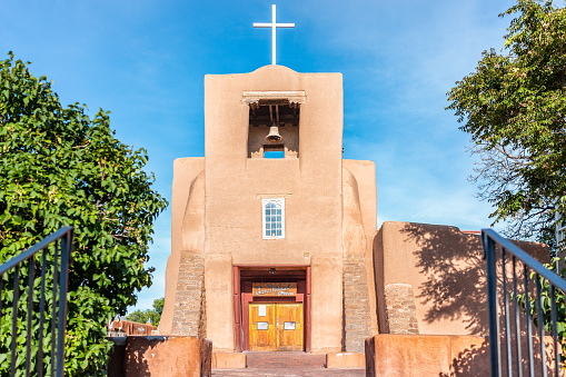 Santa Fe, USA - June 14, 2019: San Miguel Mission chapel oldest church in the United States with adobe pueblan style architecture, blue cross and blue sky