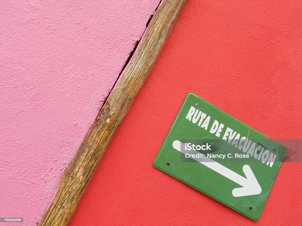 Rosa, rosso muro, segno di percorso di evacuazione In spagnolo, freccia che indica - Foto stock royalty-free di Ambientazione esterna