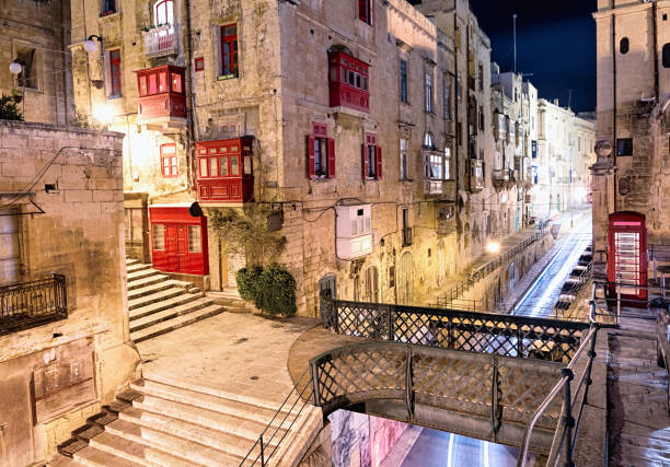 Night view of Maltese street with vintage British red telephone box a the tiny bridge, connecting old town and St Barbara Bastion, Valletta, Malta.