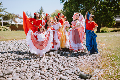 A group of Hispanic girls prepare for their performance of traditional Colombian dance at a local community theater.