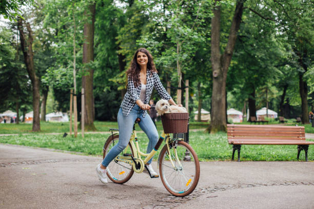 Woman smiling when riding bicycle with dog in the basket
