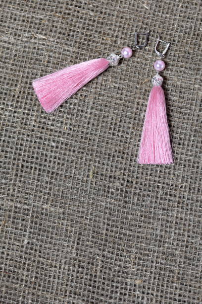 istock Earrings, tassels lie on a rough linen fabric. View from above. 1161646251